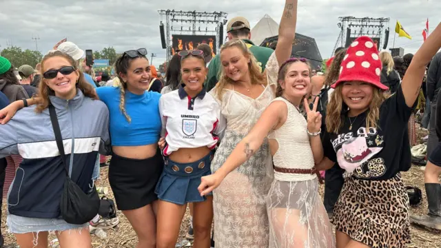 Six girls pose for the camera in a crowd at Glastonbury