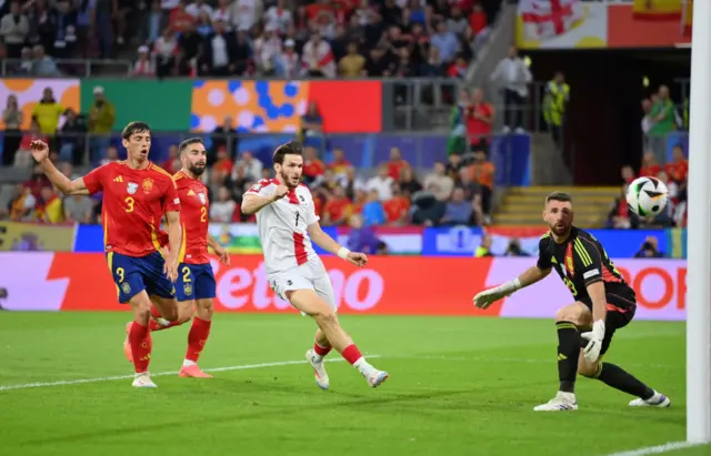 Unai Simon looks at the ball as he goes into his goal