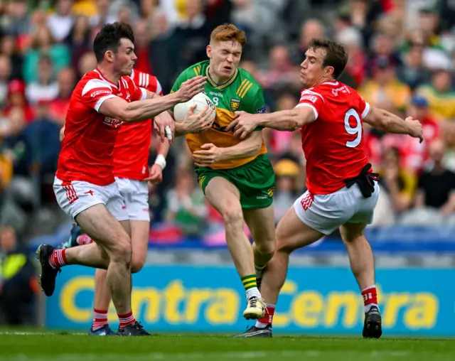 Ciaran Moore of Donegal is tackled by Dan Corcoran and Bevan Duffy of Louth