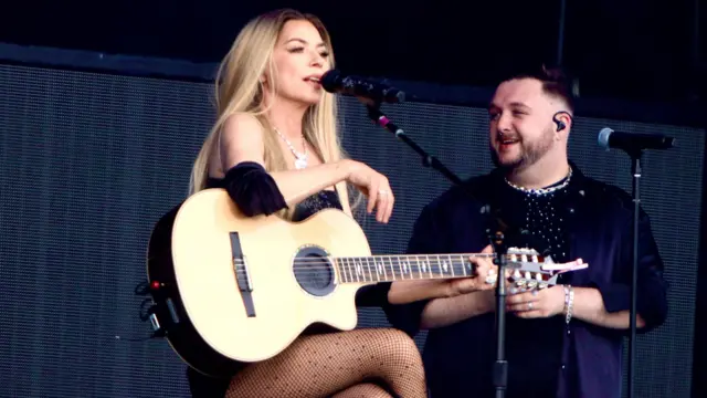 Shania Twain sits on a stool with a guitar