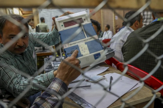 An election official shows an electronic voting machine to a polling agent, during counting of votes of India's general elections in Srinagar