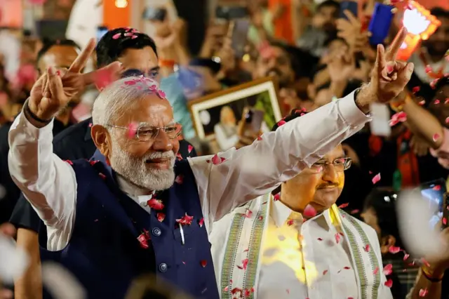 Modi making a peace sign covered in confetti