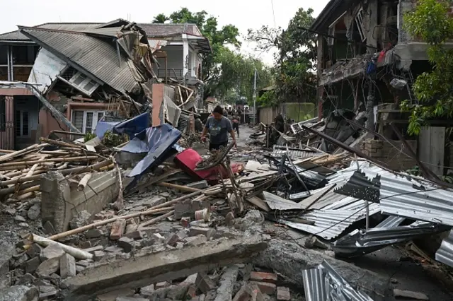 A woman seen walking through the wreckage of a building that was set on fire and vandalised by mobs in on the outskirts of Churachandpur, Manipur on 9 May 2023,