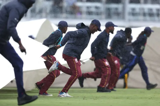 Ground staff run on with covers