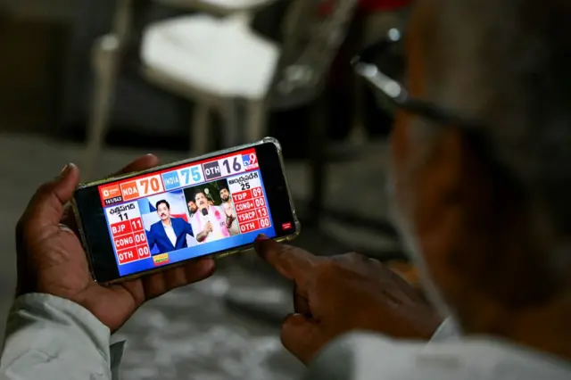 A man watches exit polls results on his phone