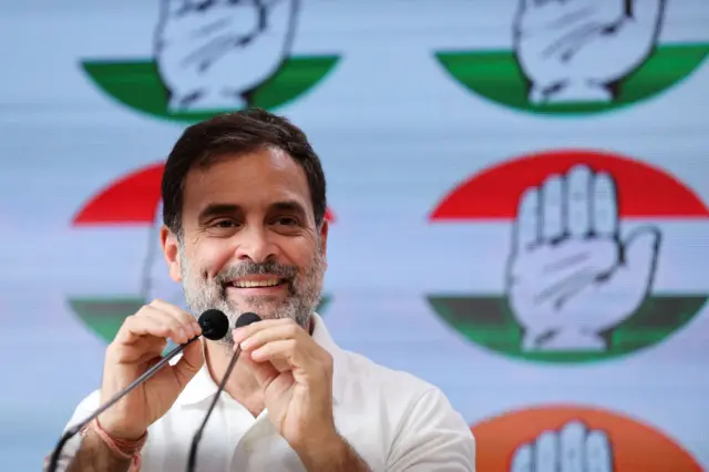 Rahul Gandhi, a leading figure of India’s main opposition party, Congress, smiles as he holds a microphone.