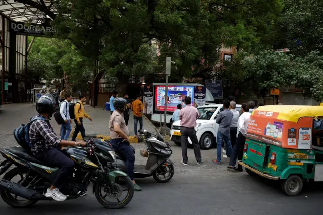 People watch the general election results on a screen installed on the side of a road, during the day of the general election results, in New Delhi, India, June 4, 2024