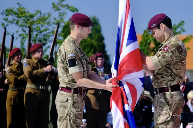 Soldiers unfurl the British flag at the Merville Battery commemoration