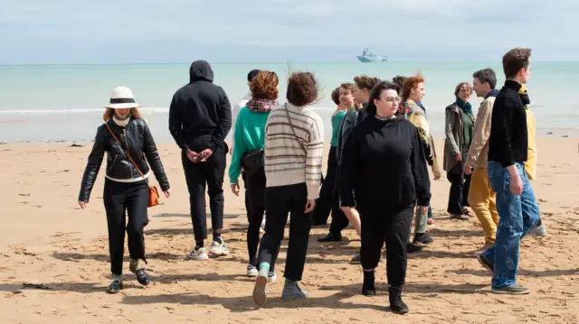 A group of young people gather on the Normandy beach