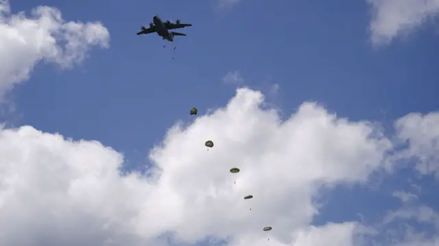 Military aircraft drops personnel in parachutes