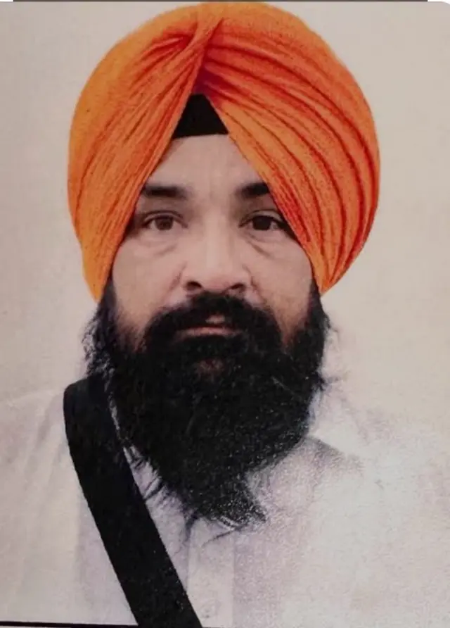 A close-up of Sarabjeet Singh Khalsa who is wearing a white kurta and an orange turban