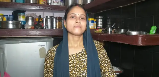 Visakha Tripathi stands in the kitchen of her home in Varanasi with a blue dupatta over her head