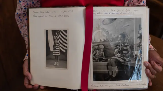 Danielle Boucherie holds old pictures of herself from a photo album