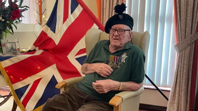 George Horner sat with a Union Jack and wearing medals