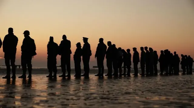 People gather to attend the ceremony on Gold Beach in Arromanches in Normandy