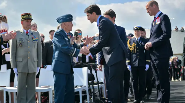Justin Trudeau shakes the hand of a veteran alongside Prince William