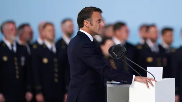 President Macron delivers a speech at a podium with military personnel in the background