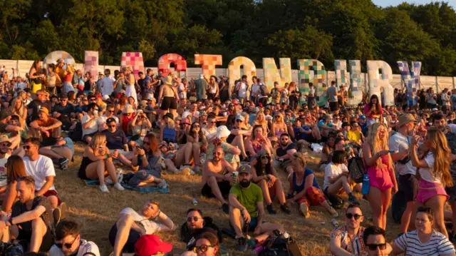 People sit on a hill at the Glastonbury festival
