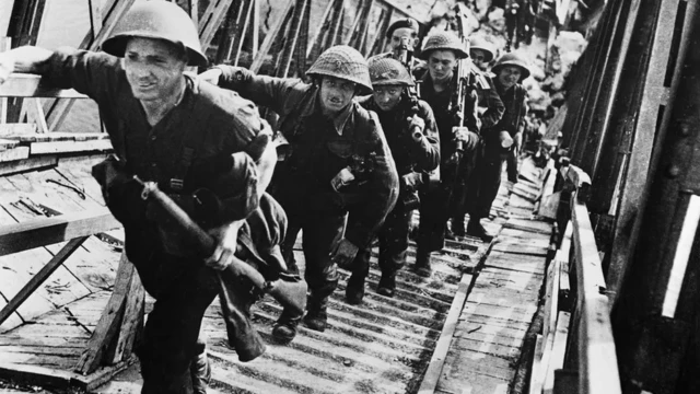 Troops walking off boats at Normandy in 1944