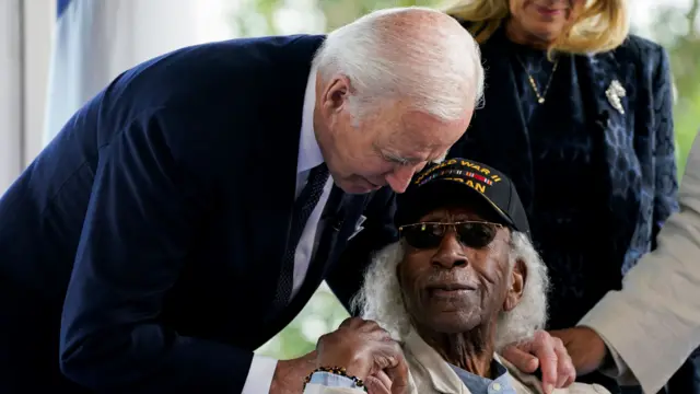 Joe Biden leans on should of World War Two veteran whose hand reaches to touch Biden's