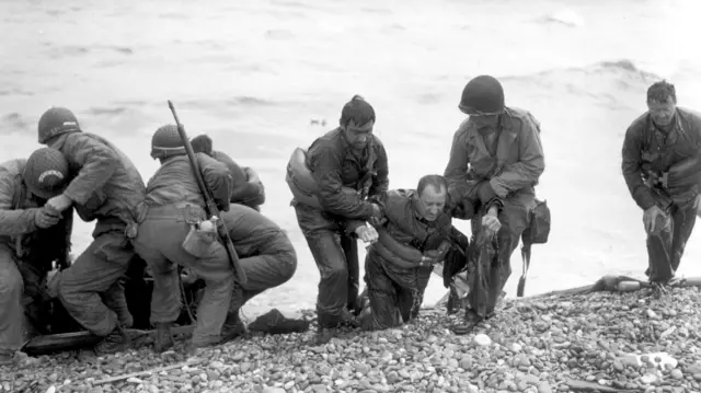 Archive photo of Members of an American landing party assist troops whose landing craft was sunk by enemy fire off Omaha beach