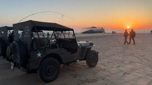 Vehicles on a beach at sunrise