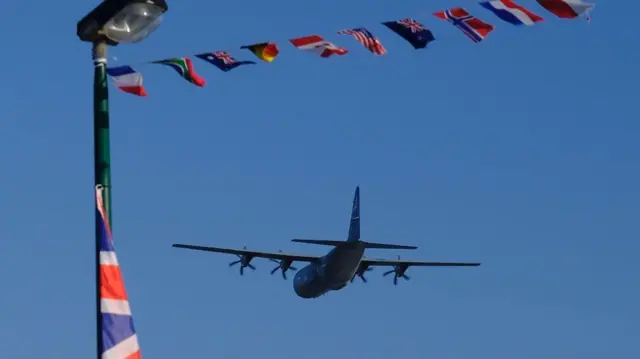 Plane flying under flags