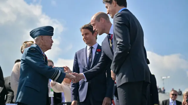 Prince William shakes hand of a Canadian veteran. Canadian Prime Minister Justin Trudeau stands next to the prince
