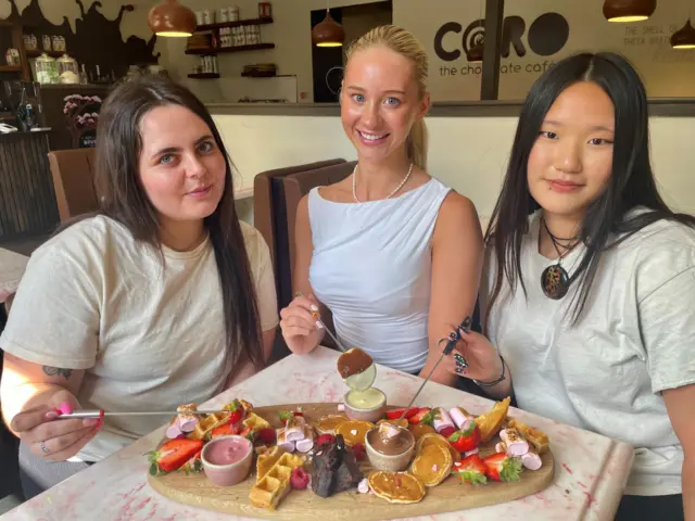 Katie McElnea, shop assistant, Lauren Stenhouse and Azeline Garrard, shop assistant with a chocolate fondue board they have prepared, inspired by Taylor Swift