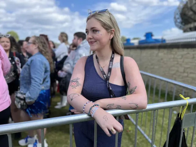 Girl leaning on a barrier with tattoos on her arms