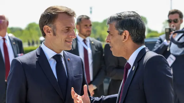 French President Emmanuel Macron talks to Prime Minister Rishi Sunak in Normandy