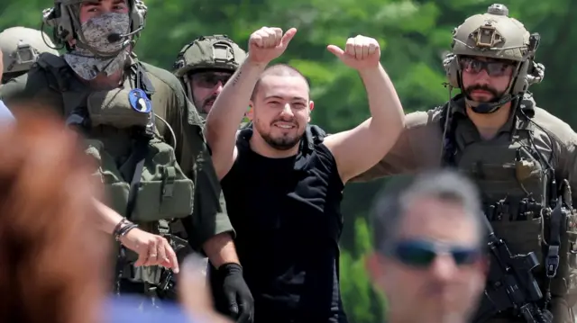 Almog Meir Jan flashes two thumbs up as he is flanked by Israeli forces