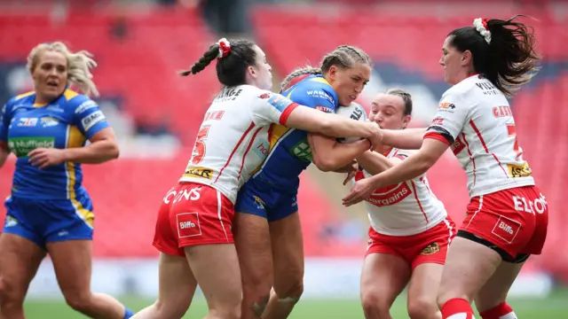 Caitlin Beevers of Leeds Rhinos in action with of Leah Burke and Faye Gaskin of St Helens