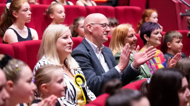 John Swinney claps while watching a performance