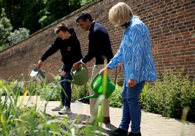 Rishi Sunak waters plants at a community garden project