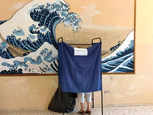 A woman stands at a voting booth during European elections at a polling station in Nafplio, Greece, on 9 June 2024