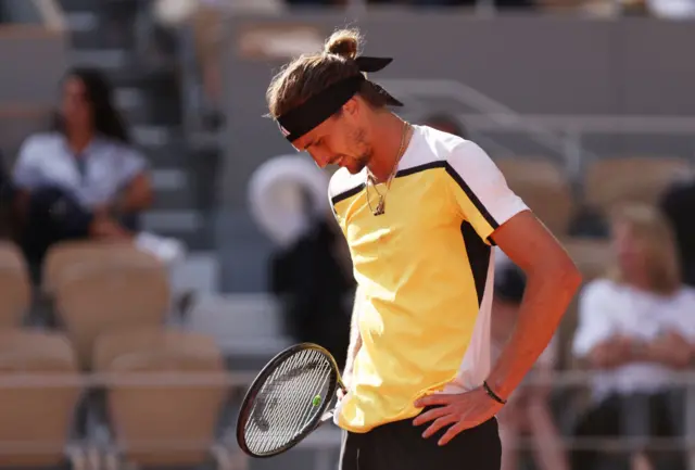 Alexander Zverev looking down with his hands on his hips