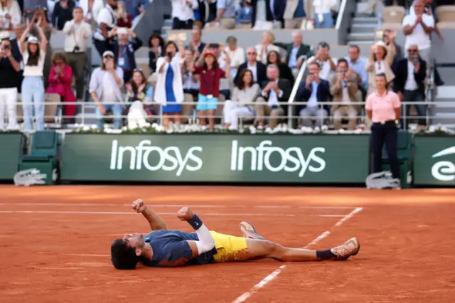 Carlos Alcaraz laying on the clay