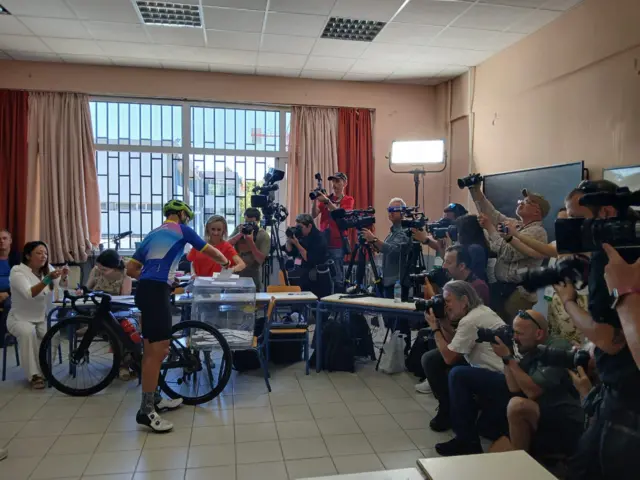 A voter in full cycling gear is casting his ballot in the EU elections while holding his bike