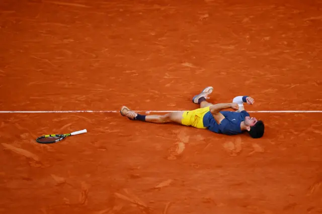 Carlos Alcaraz laying on the clay