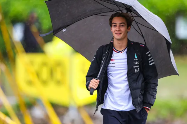 George Russell arrives in the Canada paddock under an umbrella