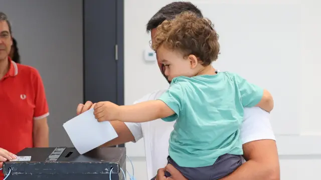 A chid helps his father to cast his ballot for the European Elections at a polling station in Lisbon,