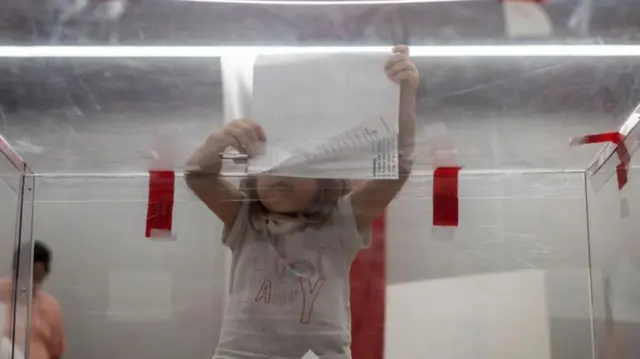 A girl puts ballot papers into a voting box in Warsaw