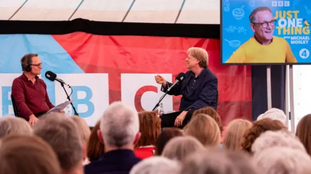 Michael Mosley sits in front of a crowd talking into a microphone in a festival tent