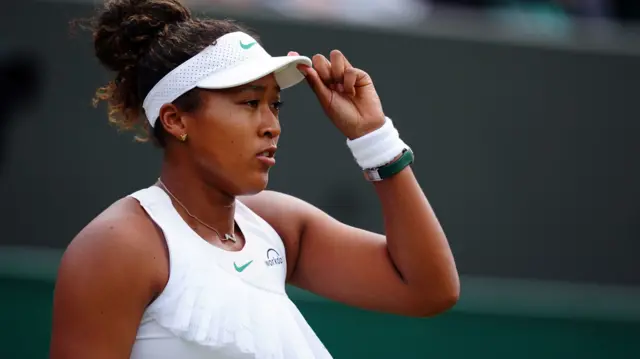 Naomi Osaka adjusts her cap