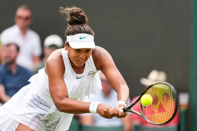 Naomi Osaka grimaces as she stretches for a ball