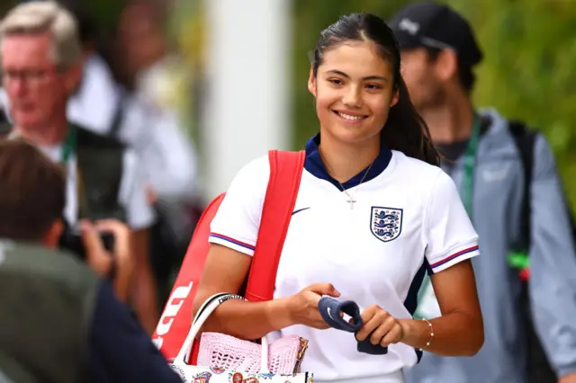 Emma Raducanu wearing an England football shirt with a bag over her shoulder