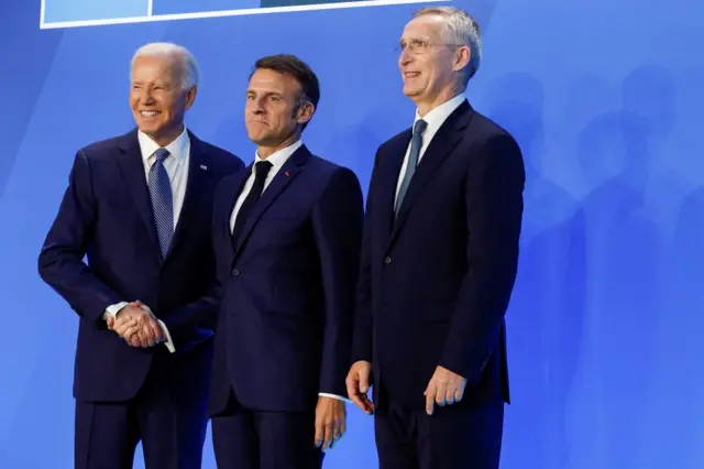 US President Joe Biden (left) shakes hadns with French President Emmanuel Macron (centre) as Nato Secretary General Jens Stoltenberg looks on