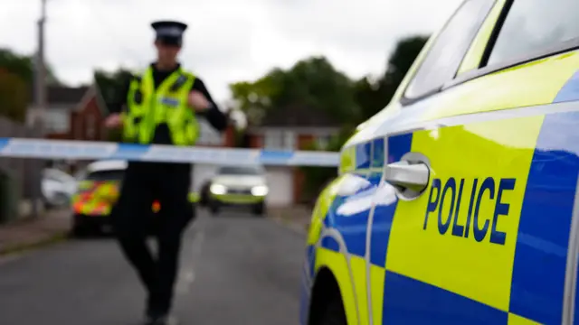 Police officer near a police car and tape