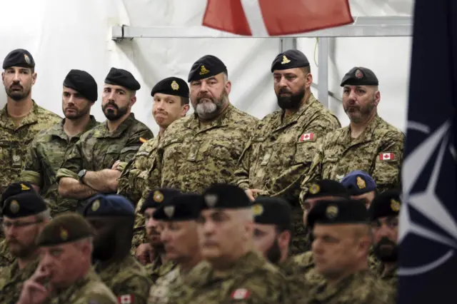 Soldiers of the NATO's multinational EFP battlegroup in Latvia attend the ceremony at the Adazi Military base